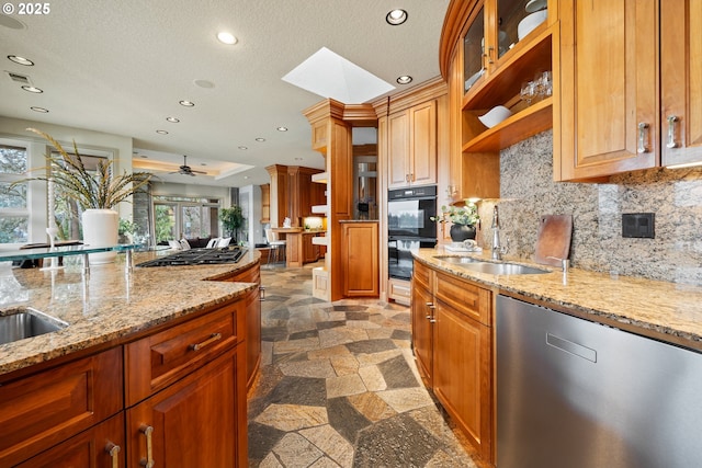 kitchen featuring sink, appliances with stainless steel finishes, a skylight, light stone countertops, and ornate columns