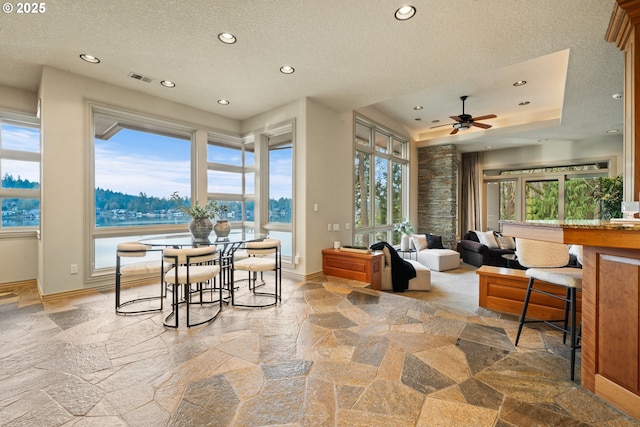 interior space with a water view, ceiling fan, and a textured ceiling