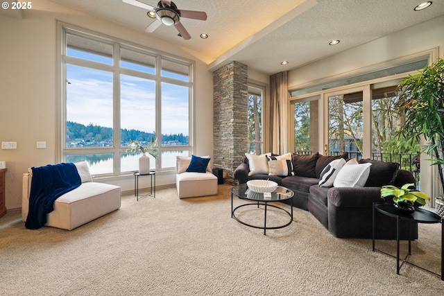 living room featuring ceiling fan, carpet, a textured ceiling, and a water view