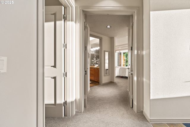 hall with light colored carpet and a textured ceiling