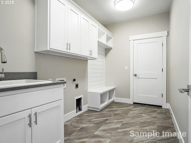 clothes washing area with electric dryer hookup, baseboards, cabinet space, and a sink