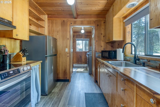 56095 Black Duck Rd, Bend, OR 97707 - kitchen with stainless steel appliances, wood ceiling with exposed beams, wooden walls, light wood-style floors, and a sink