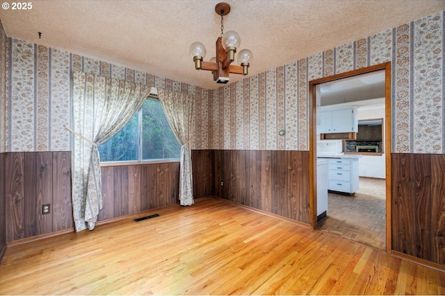 7450 SW Wilson Ave, Beaverton, OR 97008 - unfurnished dining area featuring a wainscoted wall, wallpapered walls, a chandelier, wood finished floors, and wood walls