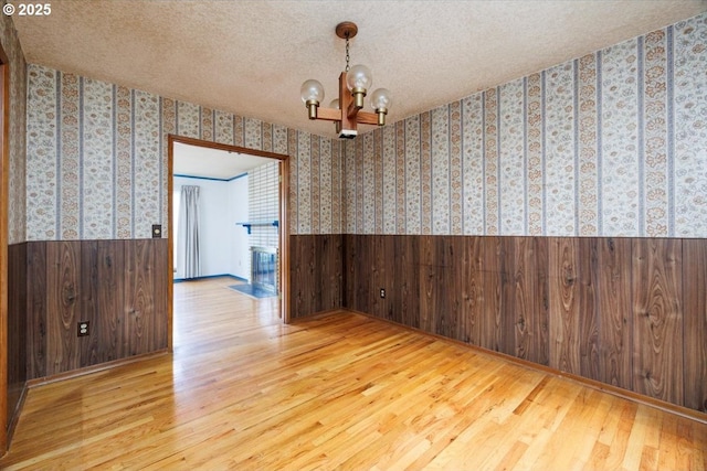 7450 SW Wilson Ave, Beaverton, OR 97008 - unfurnished dining area featuring a wainscoted wall, a chandelier, wood finished floors, wooden walls, and a textured ceiling