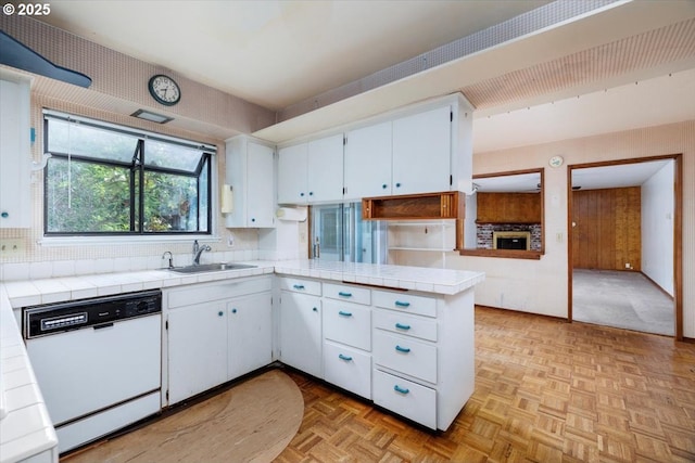 7450 SW Wilson Ave, Beaverton, OR 97008 - kitchen featuring white dishwasher, a sink, tile countertops, white cabinetry, and a peninsula
