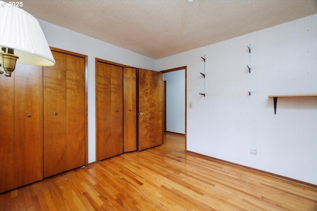 7450 SW Wilson Ave, Beaverton, OR 97008 - unfurnished bedroom with two closets, light wood-style flooring, baseboards, and a textured ceiling