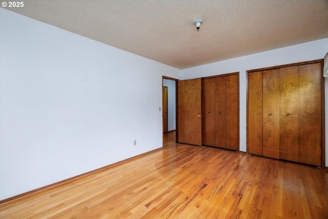 7450 SW Wilson Ave, Beaverton, OR 97008 - unfurnished bedroom featuring multiple closets, wood finished floors, and baseboards