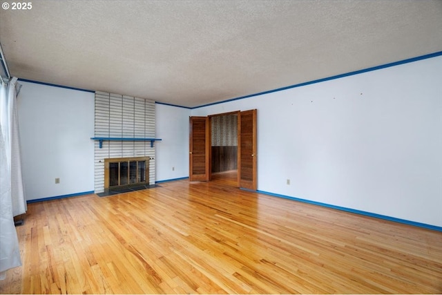 7450 SW Wilson Ave, Beaverton, OR 97008 - unfurnished living room with a textured ceiling, a brick fireplace, wood finished floors, and baseboards