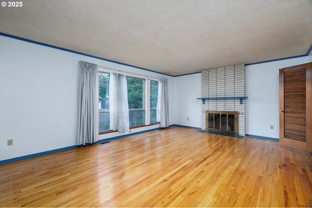 7450 SW Wilson Ave, Beaverton, OR 97008 - unfurnished living room with light wood-style floors, a fireplace, baseboards, a textured ceiling, and ornamental molding