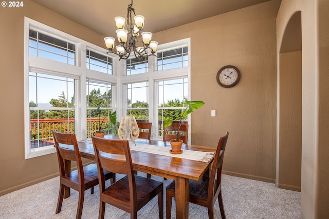 carpeted dining room with baseboards and a chandelier
