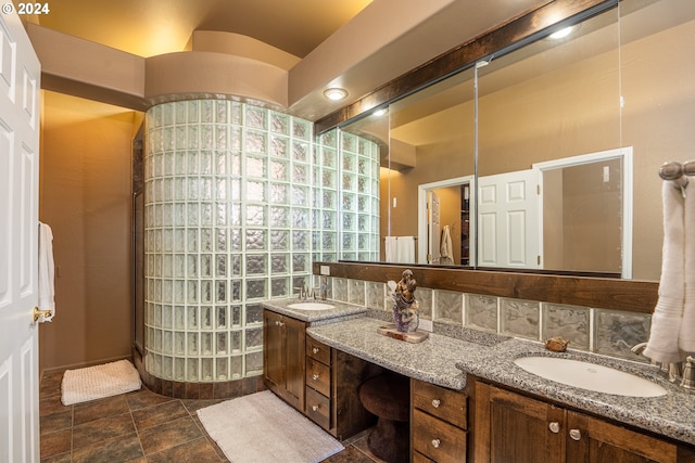 bathroom featuring double vanity, a walk in shower, and a sink