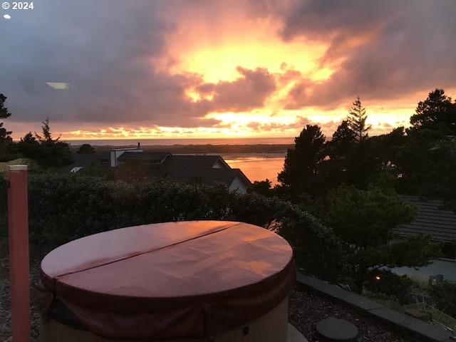view of patio with a water view and a hot tub
