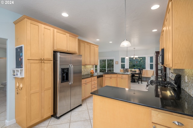 kitchen with a peninsula, appliances with stainless steel finishes, and dark countertops