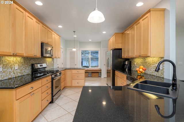 kitchen with appliances with stainless steel finishes, decorative light fixtures, a peninsula, light brown cabinetry, and a sink