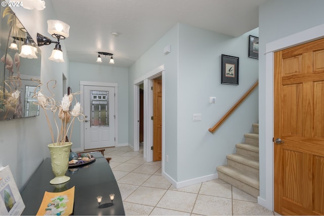 foyer featuring light tile patterned floors, baseboards, and stairway