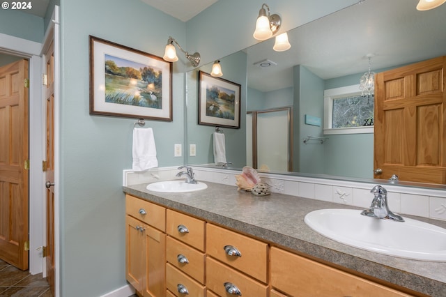 bathroom with a stall shower, a sink, and double vanity