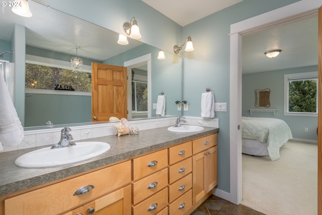 ensuite bathroom with double vanity, a sink, baseboards, and ensuite bathroom