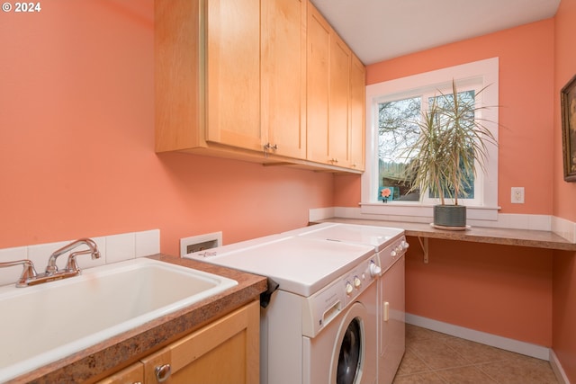 laundry room featuring light tile patterned floors, cabinet space, a sink, washer and dryer, and baseboards