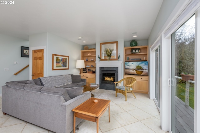 living area featuring stairs, recessed lighting, a warm lit fireplace, and light tile patterned floors