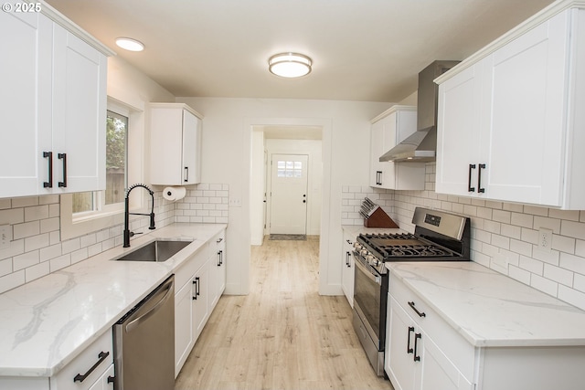 1540 Juniper St, Junction City, OR 97448 - kitchen with stainless steel appliances, wall chimney range hood, a sink, light wood-type flooring, and white cabinets