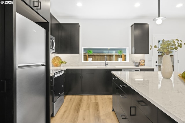 3528 NE 44th Ave, Portland, OR 97212 - kitchen with stainless steel appliances, a sink, light wood-type flooring, dark cabinetry, and recessed lighting
