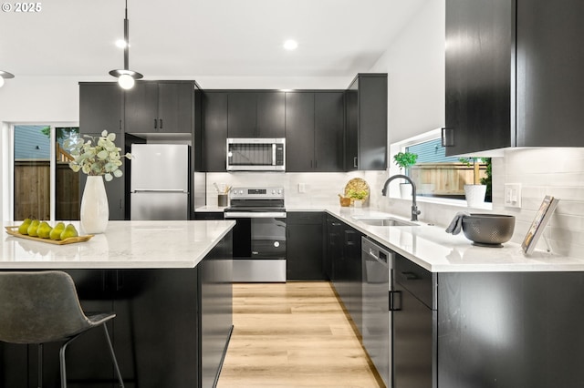 3528 NE 44th Ave, Portland, OR 97212 - kitchen featuring stainless steel appliances, a sink, dark cabinets, light wood-style floors, and recessed lighting