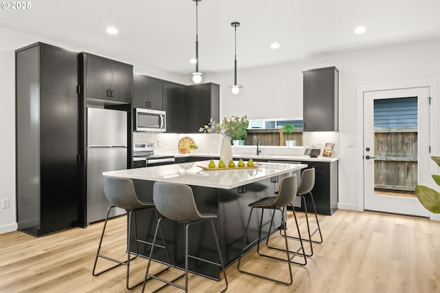 3528 NE 44th Ave, Portland, OR 97212 - kitchen with appliances with stainless steel finishes, dark cabinets, a breakfast bar area, light countertops, and pendant lighting