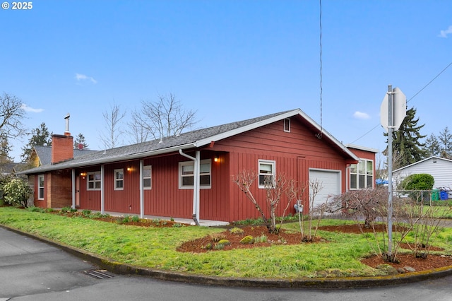 view of side of property with a detached garage, fence, and a chimney