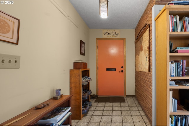 doorway with a textured ceiling and light floors