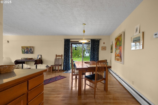 dining space featuring light wood finished floors, baseboard heating, and a textured ceiling