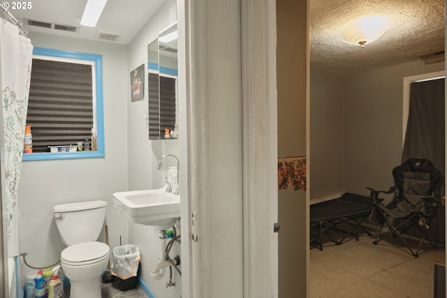 full bath with toilet, baseboards, visible vents, and a textured ceiling