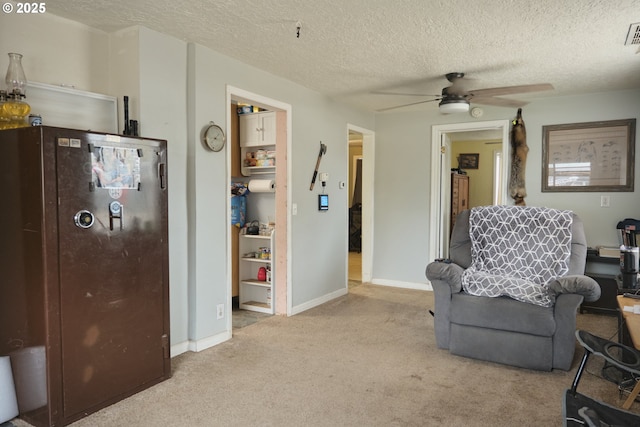 living area featuring baseboards, carpet floors, a textured ceiling, and a ceiling fan