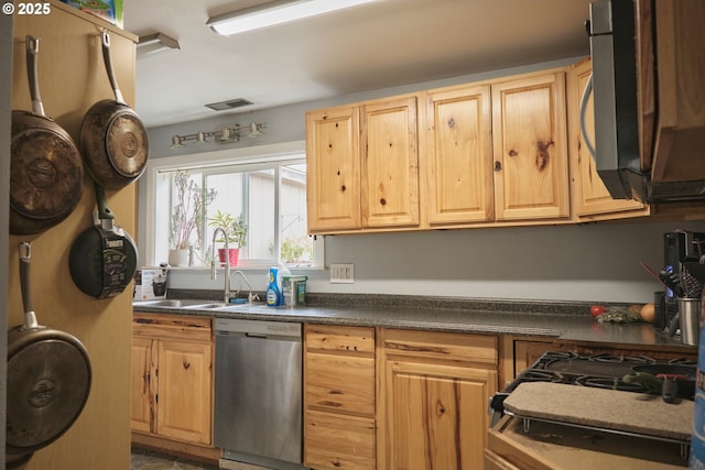 kitchen featuring visible vents, light brown cabinetry, a sink, appliances with stainless steel finishes, and dark countertops