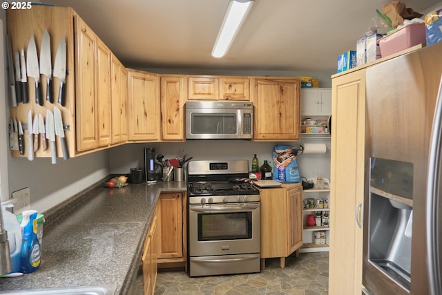 kitchen featuring dark countertops, stone finish floor, and appliances with stainless steel finishes