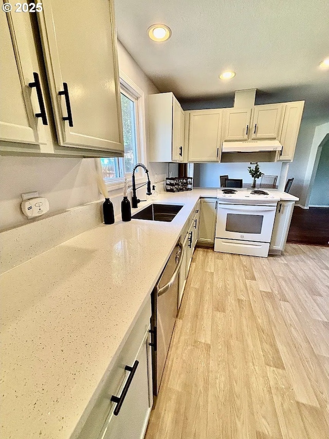12708 NE 46th St, Vancouver, WA 98662 - kitchen with electric stove, under cabinet range hood, stainless steel dishwasher, light wood-type flooring, and white cabinetry