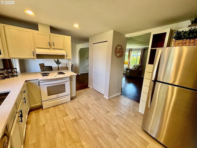 12708 NE 46th St, Vancouver, WA 98662 - kitchen featuring freestanding refrigerator, white electric range, under cabinet range hood, light countertops, and light wood-style flooring
