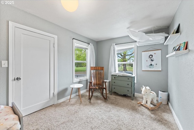living area with baseboards, carpet flooring, and a textured wall
