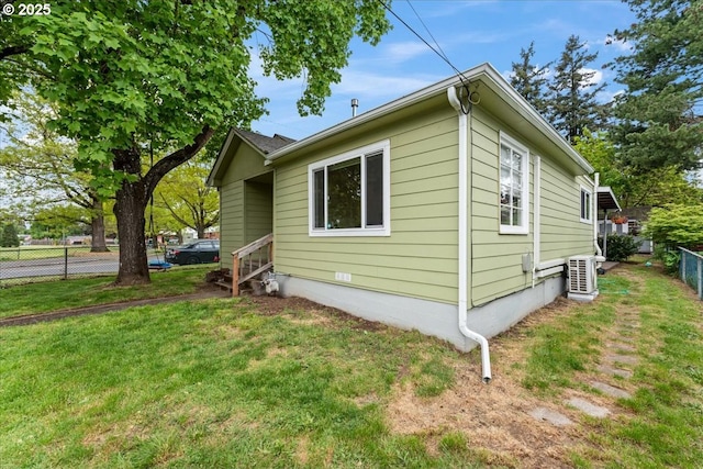 view of property exterior featuring a yard, fence, ac unit, and cooling unit