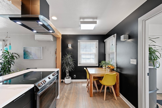 1090 Maple Dr, Eugene, OR 97404 - kitchen featuring stainless steel electric range oven, a wall mounted AC, baseboards, light wood-style flooring, and wall chimney range hood