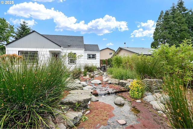 1090 Maple Dr, Eugene, OR 97404 - rear view of house featuring roof with shingles and a small pond
