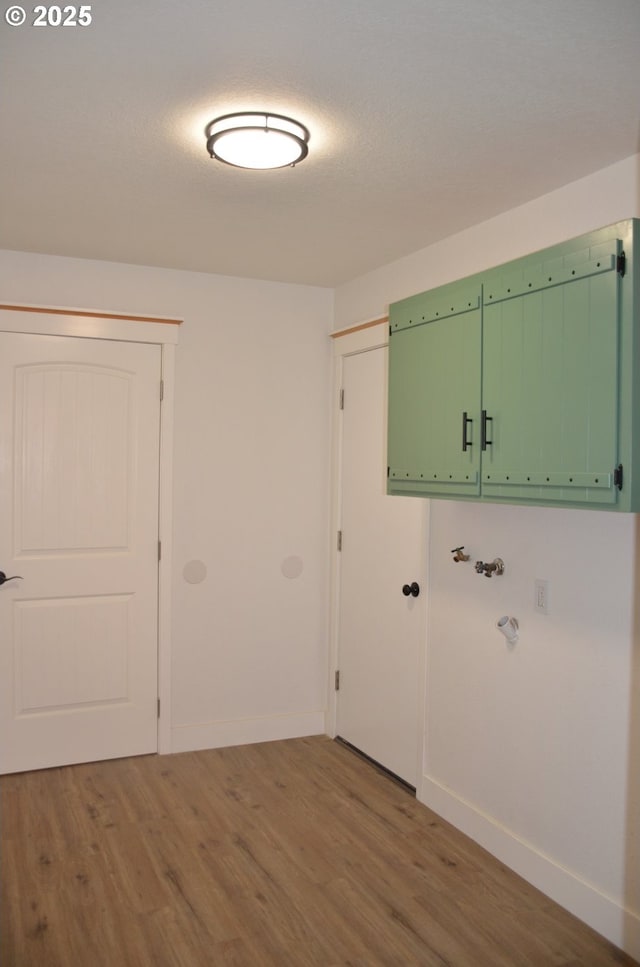 laundry area with a textured ceiling and light hardwood / wood-style flooring