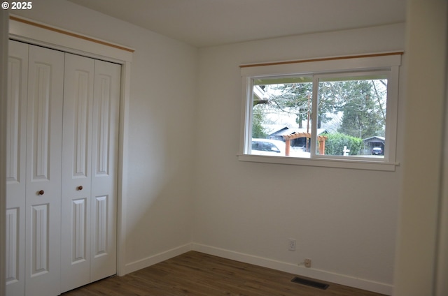 unfurnished bedroom featuring dark wood-type flooring and a closet