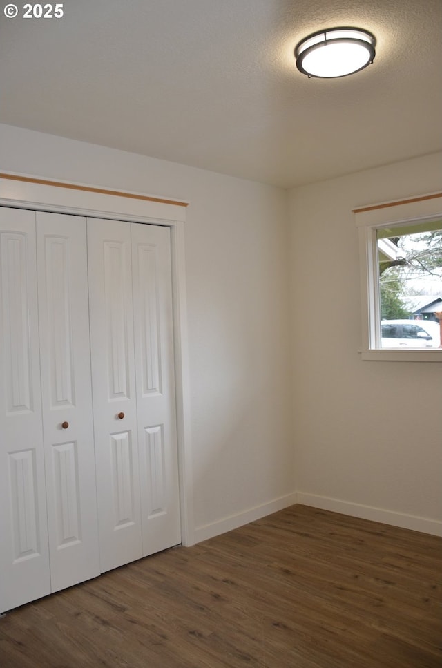 unfurnished bedroom with dark wood-type flooring, a closet, and a textured ceiling