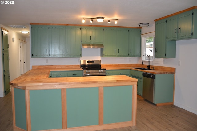 kitchen with butcher block counters, green cabinetry, and appliances with stainless steel finishes