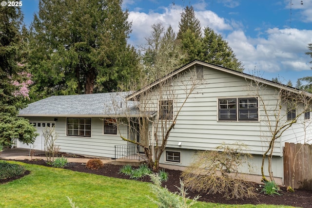 view of front of property with a front yard, an attached garage, and fence