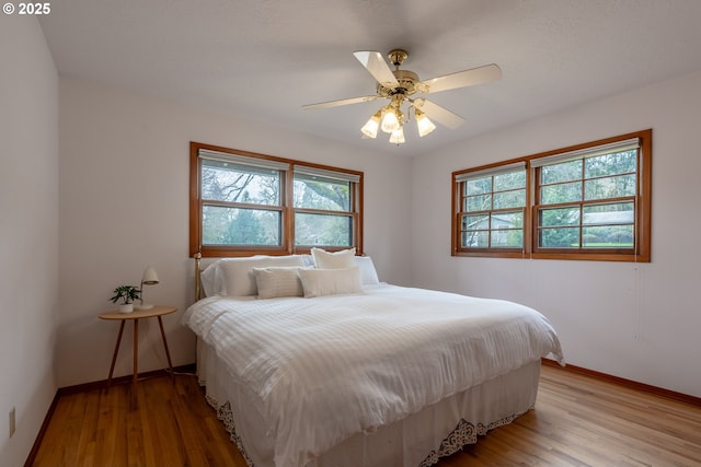 bedroom with ceiling fan, light wood-type flooring, and baseboards