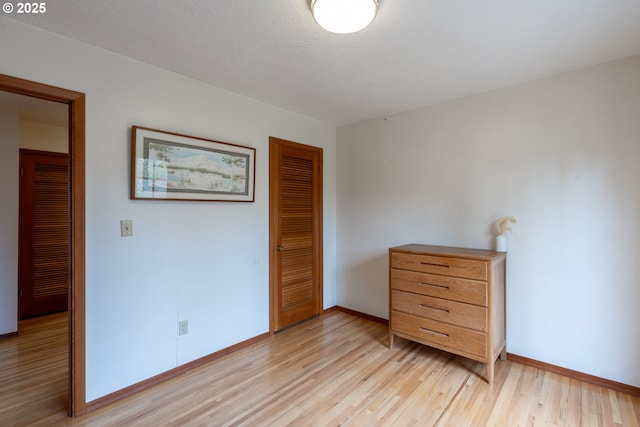 bedroom with light wood-type flooring, a closet, and baseboards