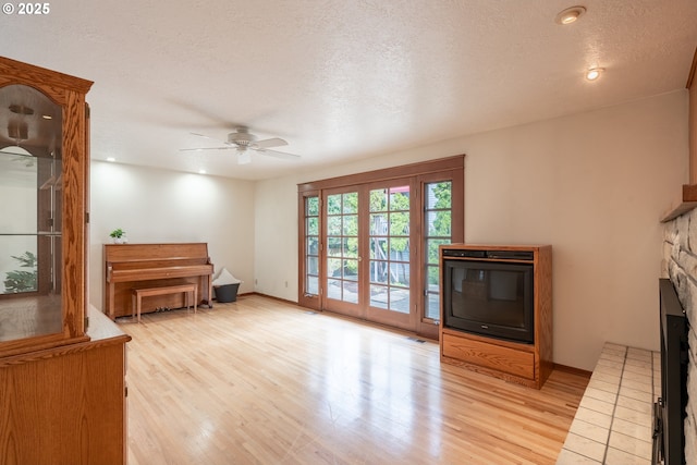 unfurnished room with baseboards, a fireplace, a textured ceiling, and light wood-style floors