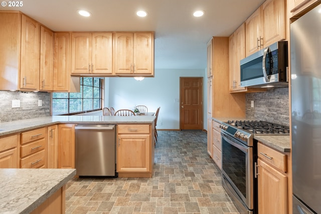 kitchen featuring stone finish floor, light brown cabinets, stainless steel appliances, and light countertops