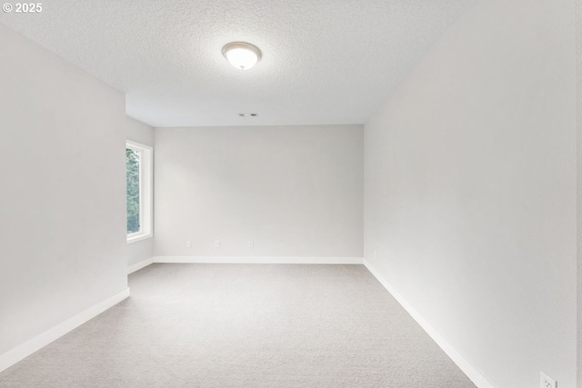 empty room with a textured ceiling, carpet flooring, and baseboards